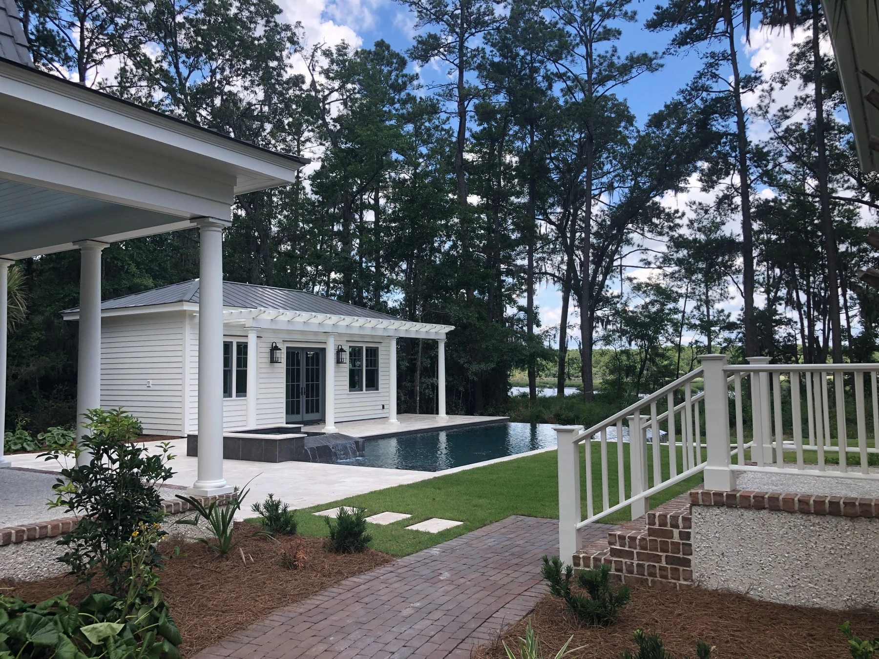 Bluffton home with a private infinity pool, white pavilion, and wooded garden
